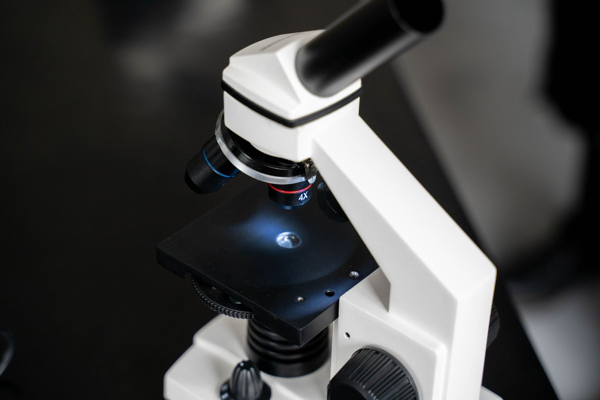 Close-up of an unbranded compound microscope showing its objective turret, stage, and focus controls