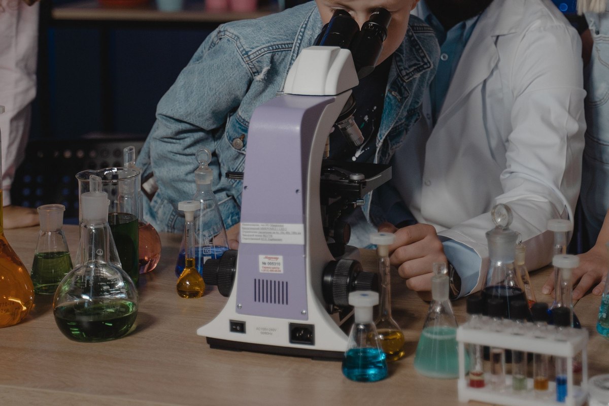 Student examining a specimen with a compound microscope during a classroom science activity